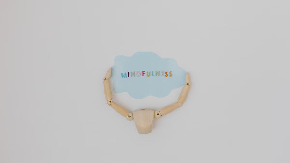 Minimalist image of a wooden figure holding a speech bubble saying 'Mindfulness'.